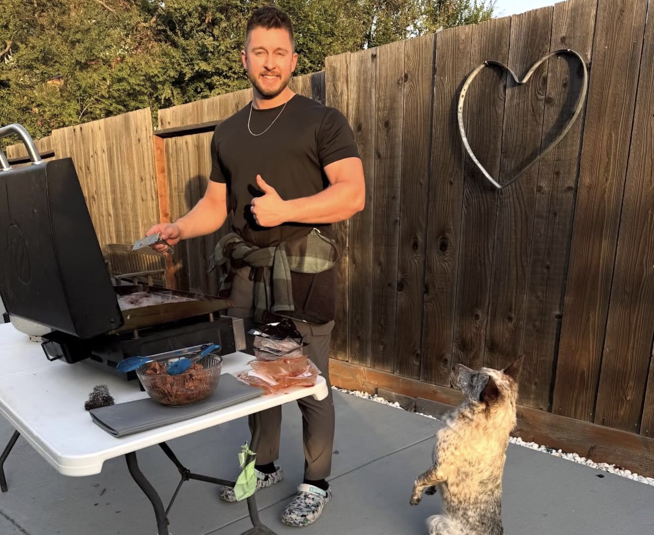 Dylan grilling meal-prep protein in the backyard while his cattle dog sits up begging